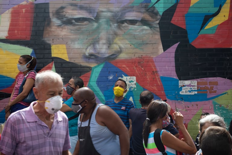 Peatones caminan frente a un mural que retrata al expresidente Hugo Chávez en Caracas, el pasado 2 de julio.
