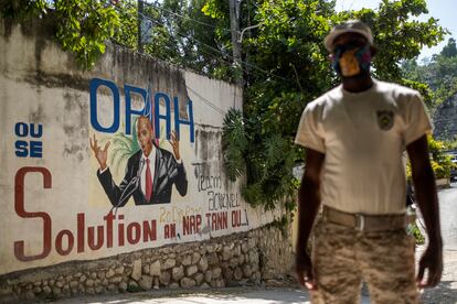 A Haitian policeman near a mural of the assassinated President Jovenel Moïse.