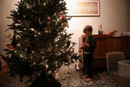 Un niño con mascarilla decora un árbol de Navidad en Nueva York.
