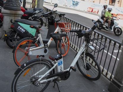 Bicicletas y motos de varias empresas de alquiler, ayer, en una calle del centro de Madrid.