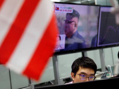 Un operador del mercado de divisas en Tokio (Japón) con una imagen de fondo del dictador norcoreano Kim Jong un en una pantalla.  
