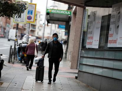 Un hombre camina con una maleta en Madrid. Luis Sevillano / EL PAÍS