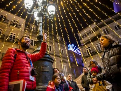 El guía José Manuel Pájaro acompaña a un grupo de turistas en el centro histórico de Vigo en un 'freetour' por las luces navideñas.