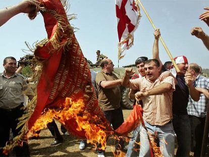 Un grupo de georgianos quema una bandera de la época soviética frente a soldados rusos en la localidad de Chorotchku.