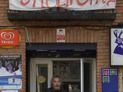 Un vecino sale de una tienda con una pancarta en defensa de las urgencias de Chiloeches.