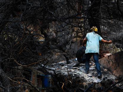 Un operario camina entre los escombros de una casa calcinada en Melloula (Argelia), este miércoles.