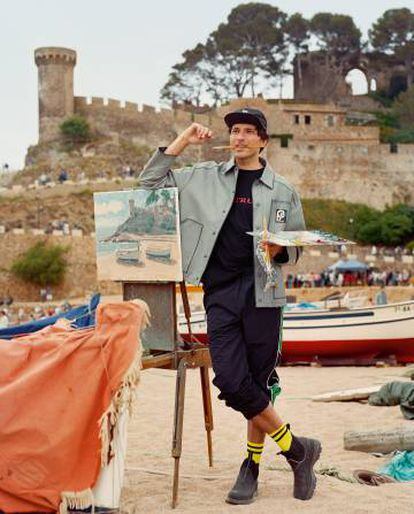 Andrés se ha puesto abrigo y botas Prada, camiseta y pantalón Shoop y calcetines Alyx. Al fondo, el Castillo de Tossa de Mar.