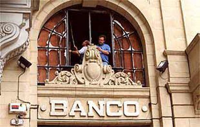 Dos personas revisan los destrozos causados por la bomba de ETA en la sede central donostiarra del Banco Guipuzcoano.