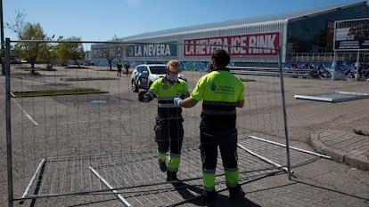 Dos operarios colocan una verja en el exterior del Palacio de Hielo de Majadahonda, este viernes.