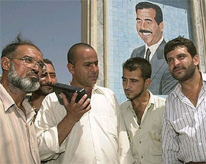 Un grupo de iraquíes escucha el discurso de Sadam Husein, ante un retrato del dictador, ayer en Bagdad.