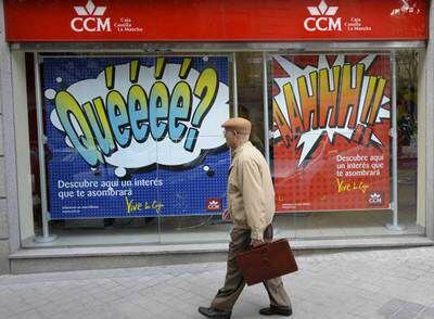 Un hombre observa los carteles publicitarios expuestos en una sucursal madrileña de Caja Castilla La Mancha.