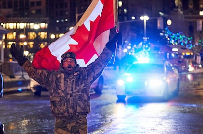 Un hombre camina en la noche del 9 de febrero entre los camiones apostados frente al parlamento de Ottawa, en Canadá, para protestar por la obligatoriedad de presentar un certificado de vacunación para cruzar la frontera de Estados Unidos.