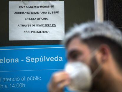Persona amb mascareta fent cua a l'Oficina de Treball de la Generalitat, a Barcelona.