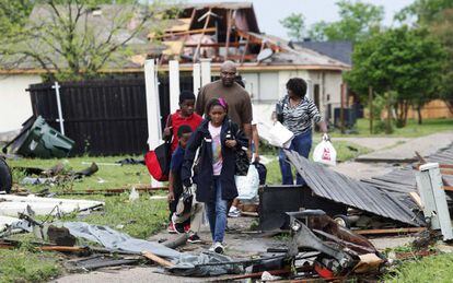 Una familia camina entre los escombros en una calle de Lancaster, Tejas, después de que una serie de tornados asolara la zona.