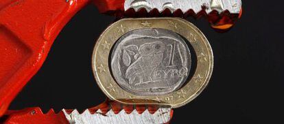 Moneda de un euro griega, aplastada por unas tenazas.