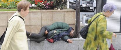 Unas mujeres ancianas pasan delante de un mendigo también de avanzada edad en Tokio, Japón.