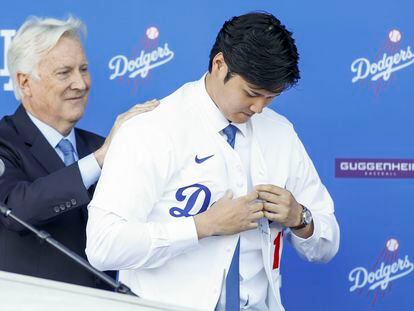 Mark Walter, uno de los dueños de los Dodgers, ayuda a Ohtani a ponerse la camiseta del equipo de Los Ángeles.