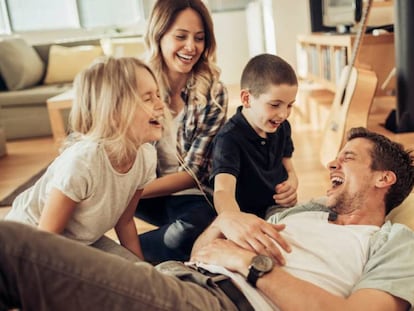 Niños y padres se ríen en el sillón.