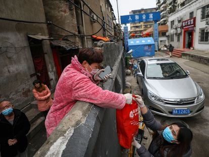 Una persona recibe una bolsa de comida en Wuhan, el 3 de marzo.