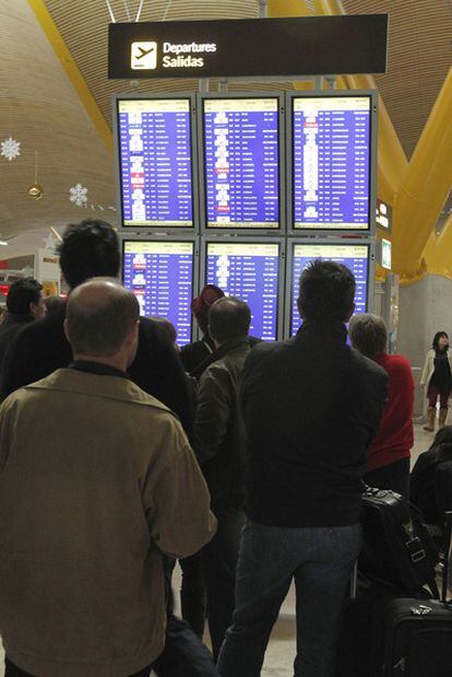 Viajeros en la T-4 de Barajas, ayer miran un panel de vuelos.