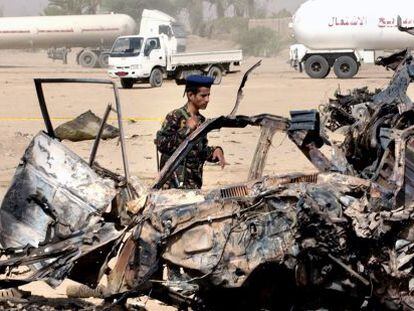 Un militar yemen&iacute; observa los restos del coche de los turistas espa&ntilde;oles.