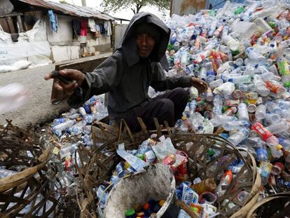 Un hombre recolecta botellas para reciclar en Indonesia.