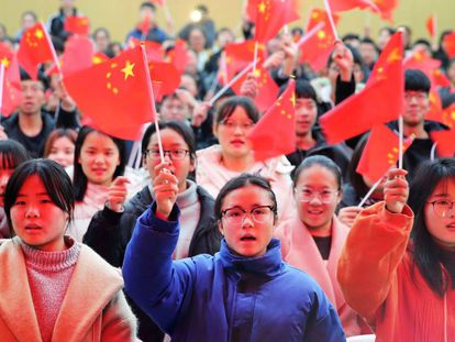 Varios estudiantes de una universidad de la provincia de Anhui ondean banderas de China.