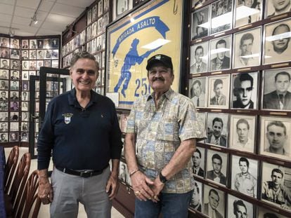 Los veteranos de Bahía de Cochinos Humberto López y Arturo Sánchez Bella posan delante de las fotos de los caídos en el museo de la Brigada 2506 en Miami el viernes, 16 de abril de 2021.