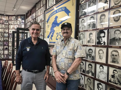 Los veteranos de Bahía de Cochinos Humberto López y Arturo Sánchez Bella posan delante de las fotos de los caídos en el museo de la Brigada 2506 en Miami el viernes, 16 de abril de 2021.