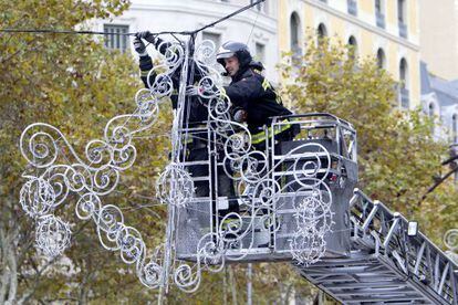 Los bomberos colocan una de las luces descolgadas en Passeig de Gràcia