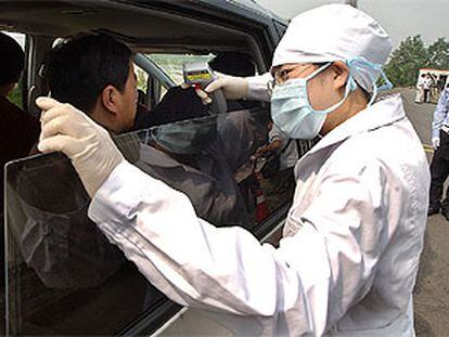 Un médico toma la temperatura a los pasajeros que salen del aeropuerto de Pekín.