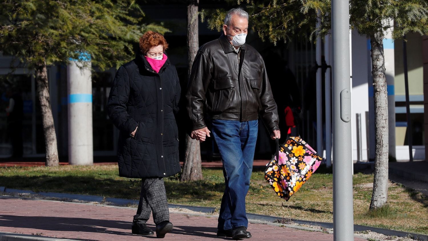 Una pareja con mascarillas vista en el exterior del Hospital de Torrejón de Ardoz. Chema Moya (EFE)
