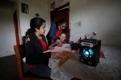 Fanny Méndez, a la derecha, madre de Marlene Beltrán, de 14 años, a la izquierda, y Felipe Beltrán, de cinco, ayuda a sus hijos en casa a hacer un cubo de papel mientras escuchan una lección de una hora transmitida por la radio Bacata Stereo, en mayo de 2020.