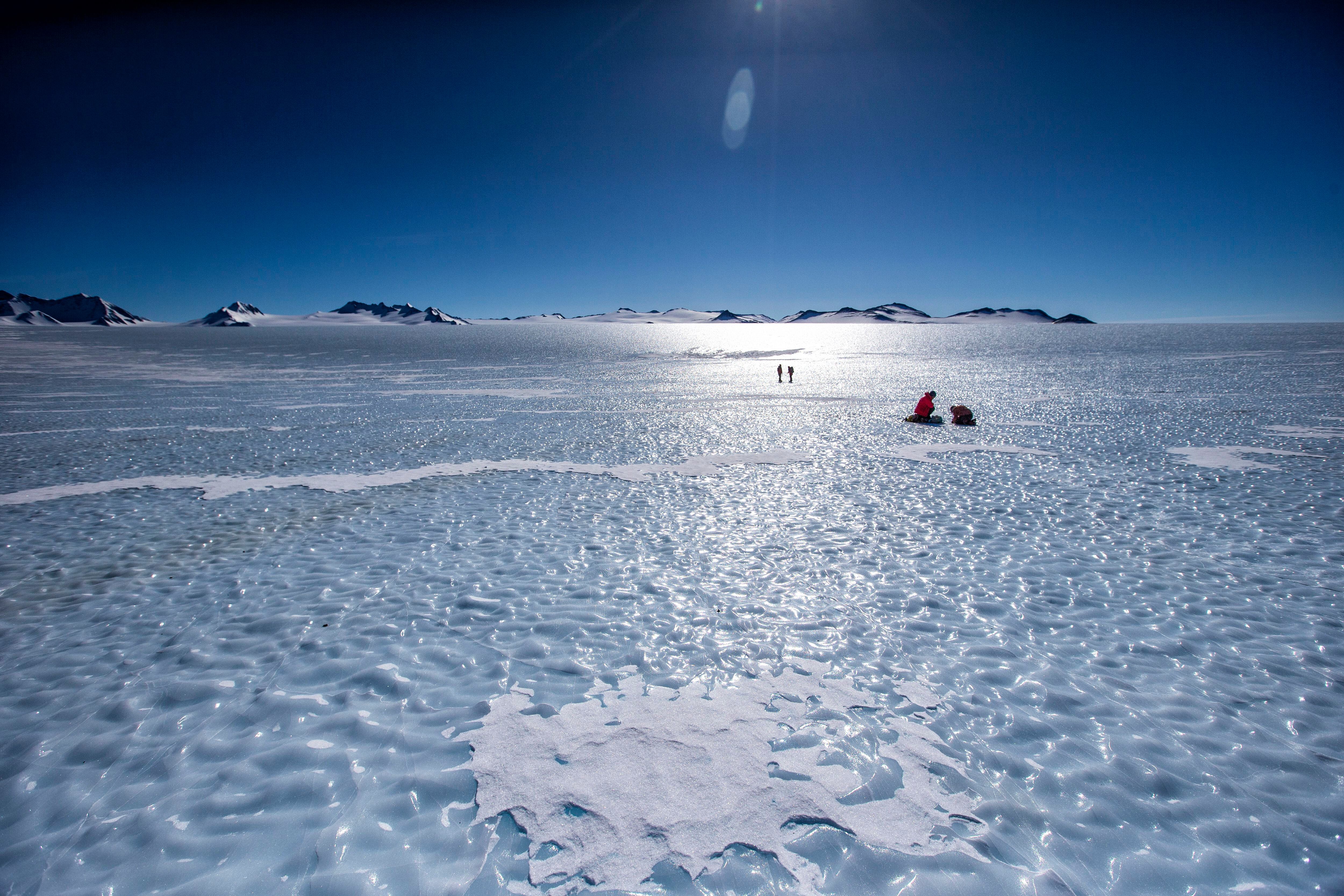 La glacióloga Veronica Tollenaar y su colega José Jorquera toman muestras de hielo, con dos exploradores militares en segundo plano.