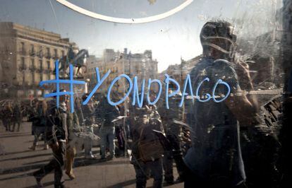 Un indignado hace una pintada referida al movimiento "Yo no pago" durante la celebración de una asamblea ciudadana del 15-M en la Puerta del Sol de Madrid al término de la manifestacion han convocado los sindicatos contra la reforma laboral del Gobierno.