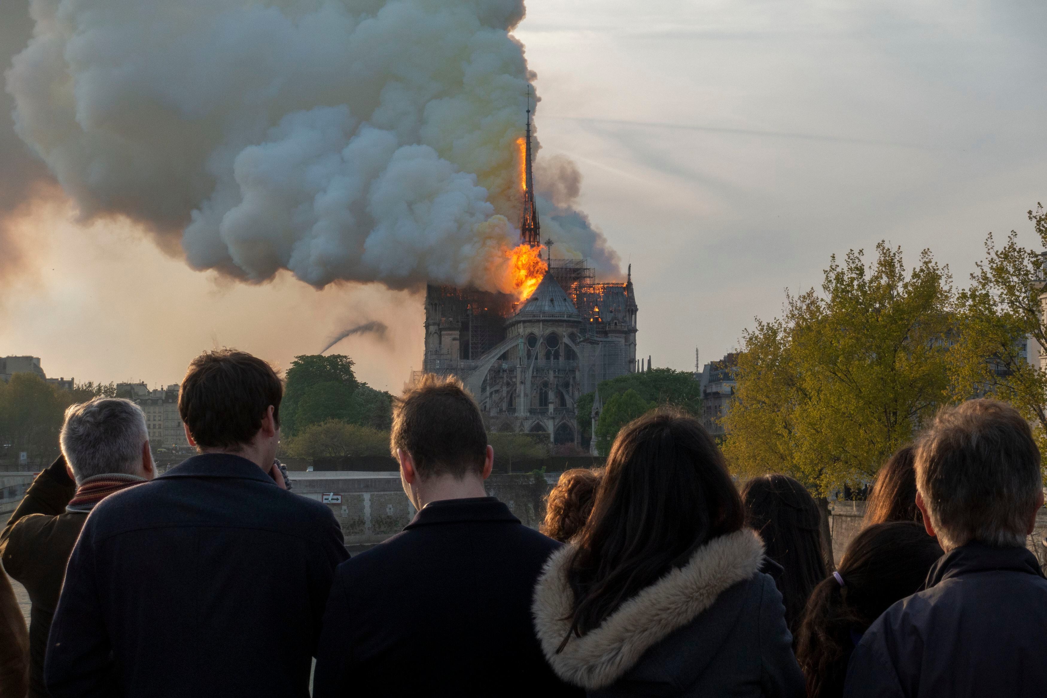 Un grupo de personas contempla, desde uno de los puentes sobre el Sena, cómo las llamas engullen Notre Dame: 15 de abril de 2019