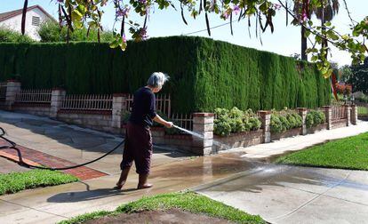 Una mujer lava con manguera la entrada de su casa en la ciudad de Monterey Park, al este de los Ángeles.