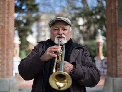 El músico Miguel, de 68 años, posa con su trompeta frente a la Biblioteca Eugenio Trías en el Parque del Retiro de Madrid.