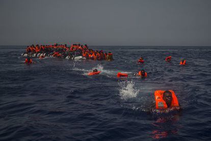 Inmigrantes africanos esperan ser rescatados por la ONG española Proactiva Open Arms tras hundirse el bote en el que navegaban en el mar Mediterráneo a unas 12 millas al norte de Sabratha (Libia), el 23 de julio de 2017.