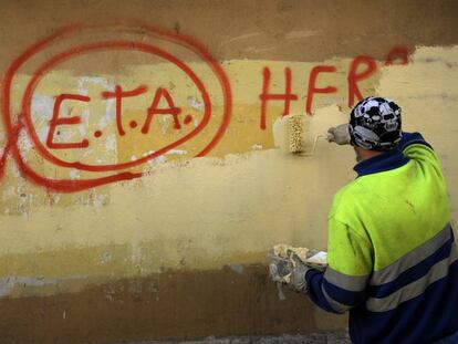 Un trabajador municipal borra una pintada con la leyenda.