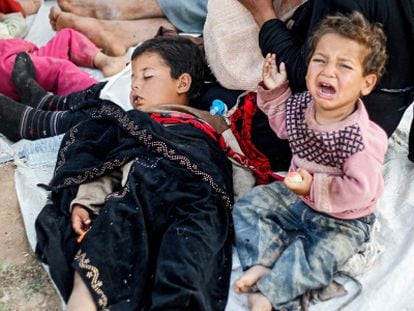 Una familia de refugiados sirios espera entre la frontera de Siria y Turquía.