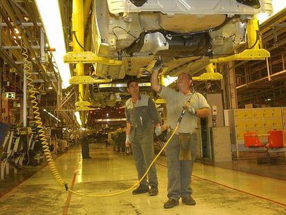 Trabajadores en una l&iacute;nea de producci&oacute;n de Opel en la planta de Figueruelas (Zaragoza)