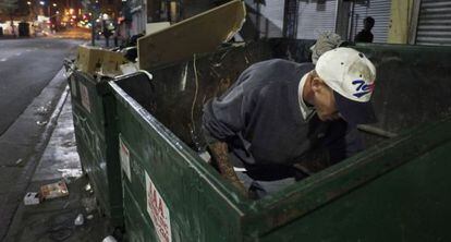 Un vagabundo busca comida en un contenedor de basura en Los Ángeles