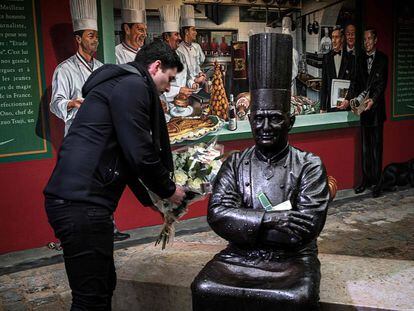 Un hombre deja un ramo de flores en la estatua de Bocuse en su restaurante en Lyon.