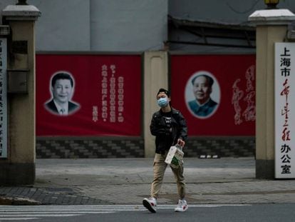 Un hombre con una máscara camina frente a los retratos del presidente chino Xi Jinping y el difunto presidente Mao Zedong, el pasado 10 de febrero en Shanghái.