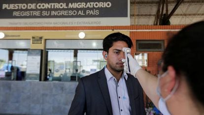 Un trabjador toma la temperatura a un hombre en Puerto Falcón (Paraguay).