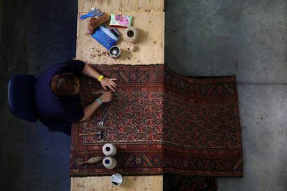 Una trabajadora repara una alfombra.