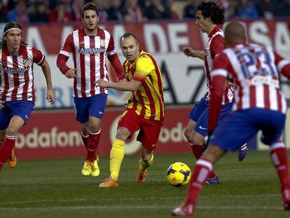 Iniesta conduce el balón rodeado de jugadores del Atlético