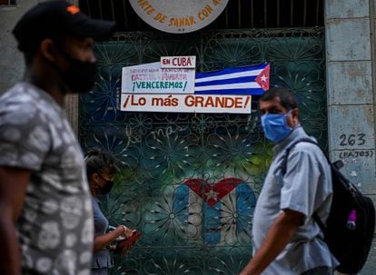 Varias personas caminan frente a una bandera de Cuba en La Habana, el 11 de noviembre.