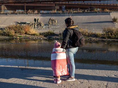 Una migrante y su hija observan a militares estadounidenses desde el lado mexicano de la frontera, en Ciudad Juárez.